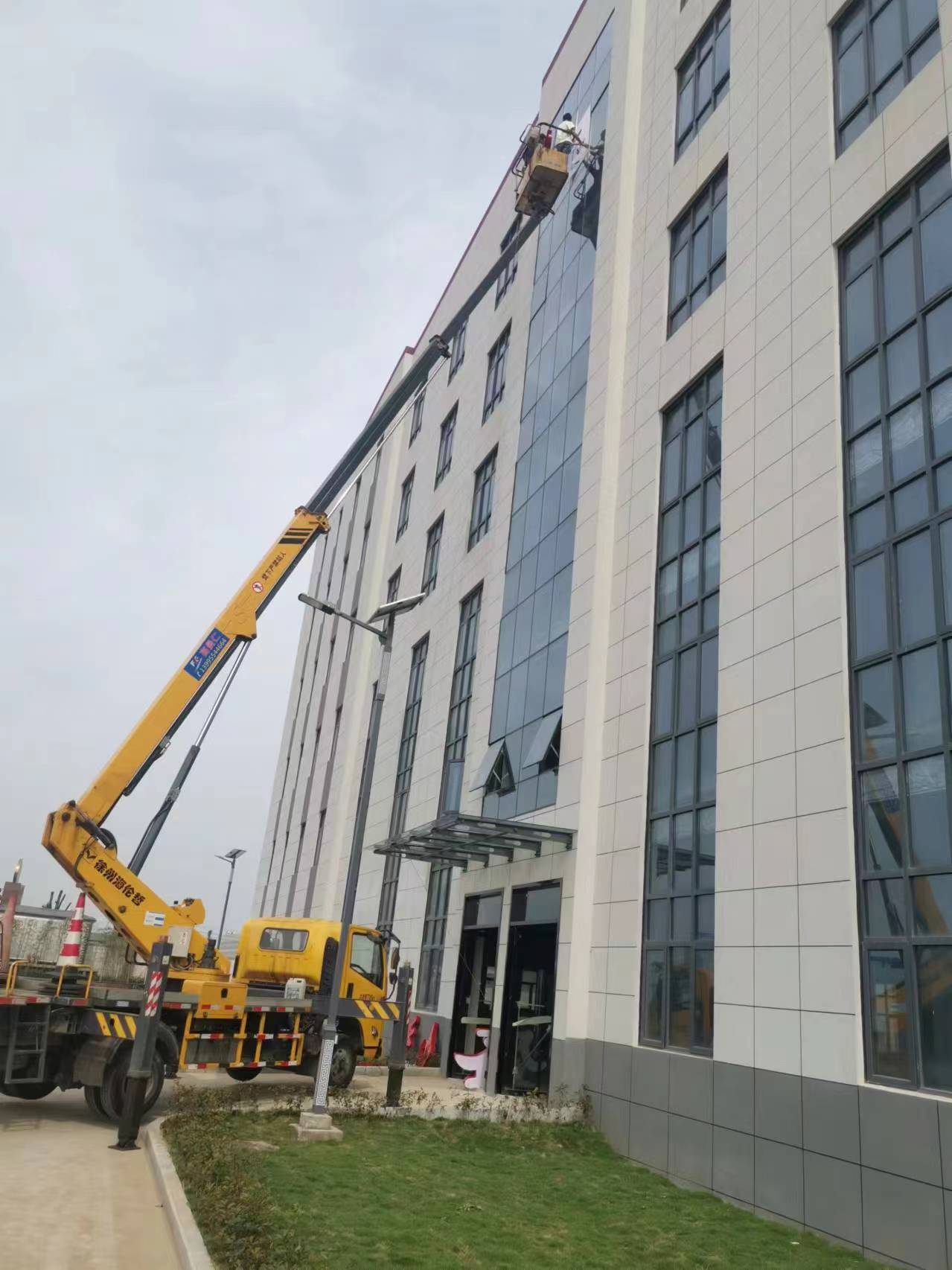 24米升降車高層樓外墻換玻璃施工現場